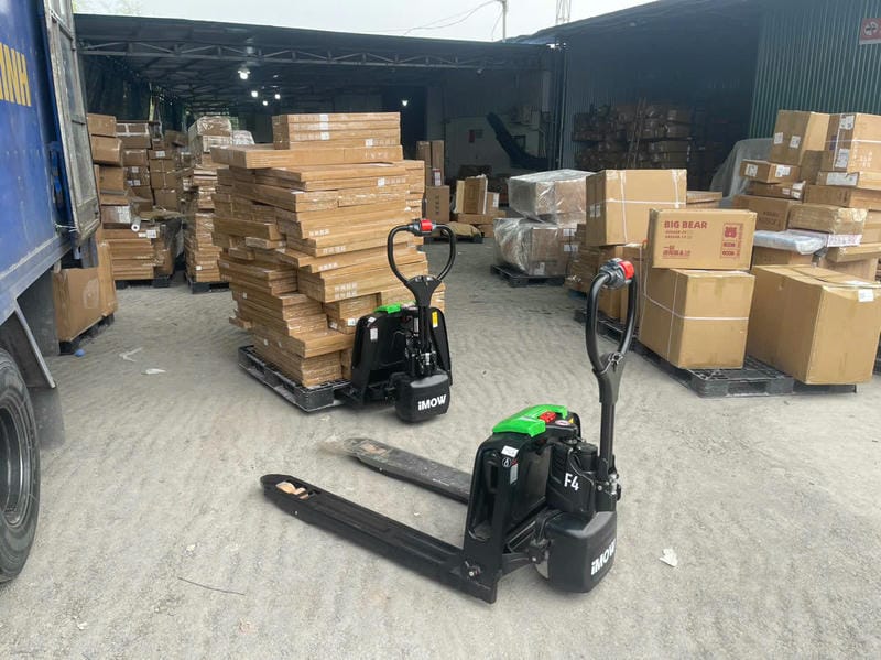Xe tay điện chỉ nâng pallet thấp để di chuyển hàng, còn stacker nâng hàng lên